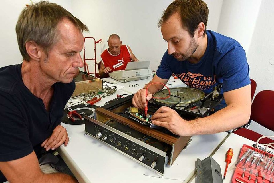 Detlef Schwarz (hinten) kümmert sich um eine Schreibmaschine, Dirk Lill (rechts) will einen Plattenspieler funktionstüchtig machen: Ein Mal im Monat ist Reparaturcafé im Quartiersladen Stühlinger. (Foto: Rita Eggstein)