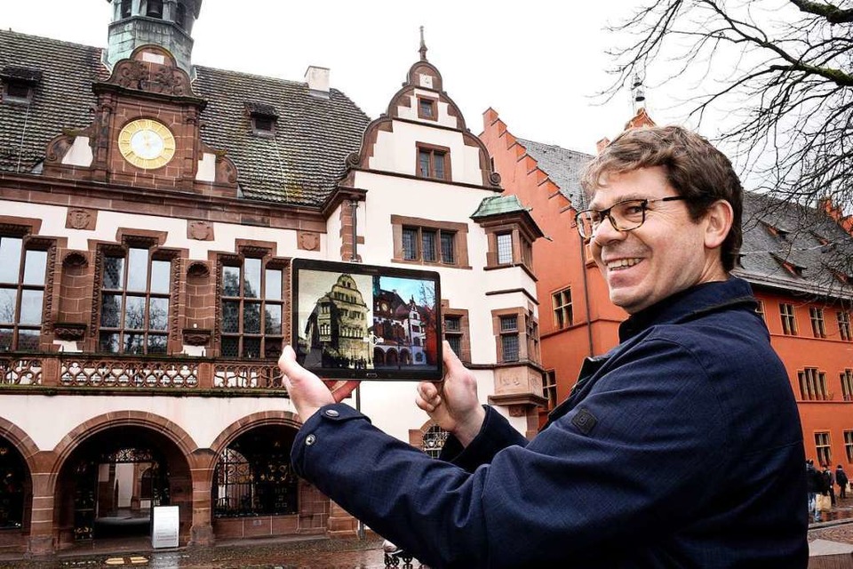 Rolf Mathis blendet zwischen historischer und heutiger Ansicht des Rathauses hin und her. (Foto: Thomas Kunz)